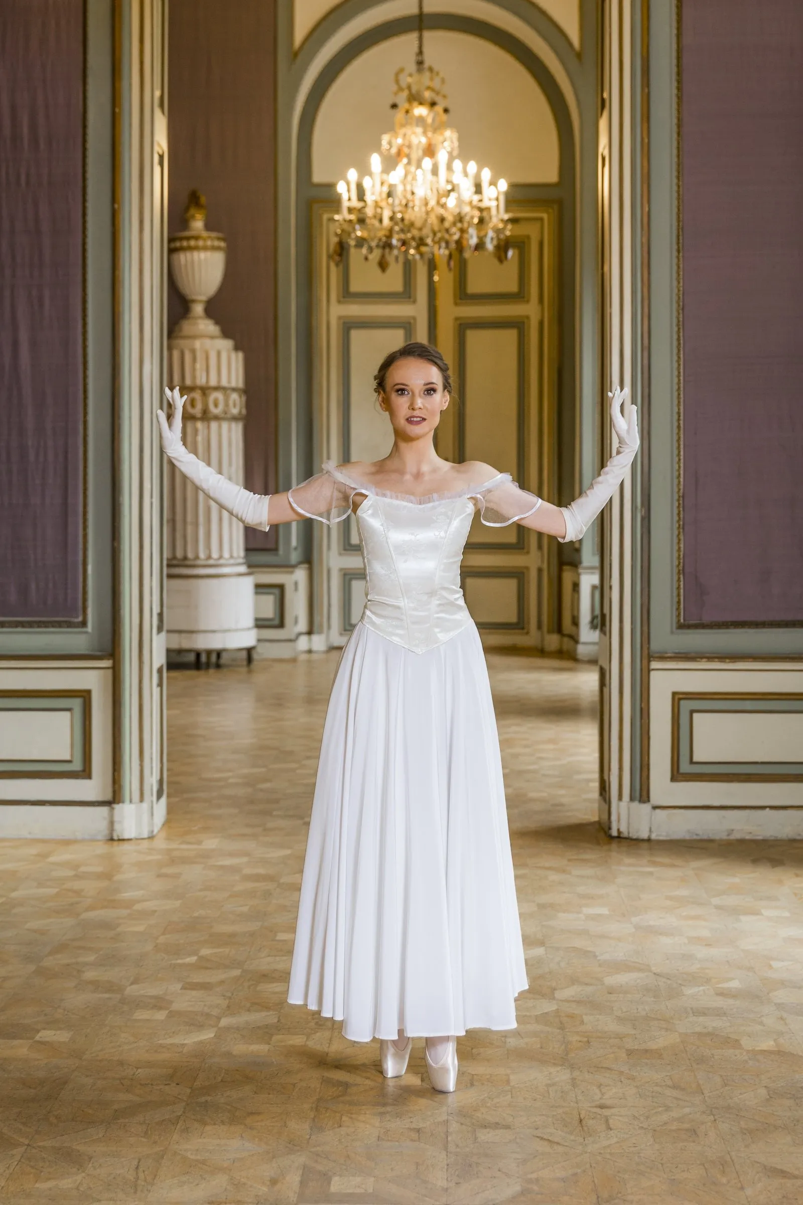 Ballet dancer in a white dress in front of a double door